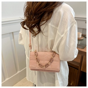 Detail of light pink pleated leather crossbody bag with decorative gold resin chain