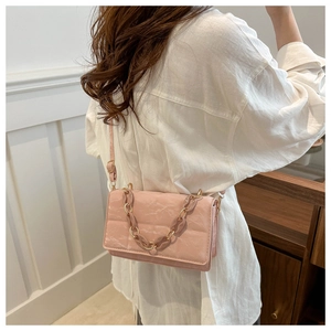 Detailed view of pink pleated textured handbag featuring a large resin and metal chain