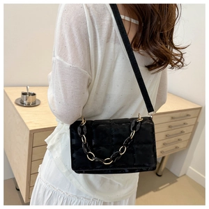 Close-up of black quilted velvet crossbody bag featuring a chunky resin chain strap