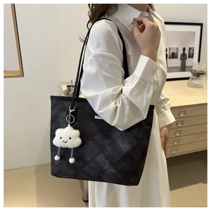 Detailed view of large black quilted tote bag with a cute plush cloud charm detail