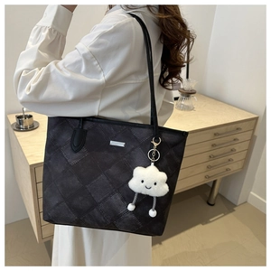 Close-up of a large tote bag with quilted gray texture and a cute smiley plush charm