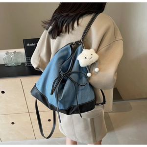 Detail of denim and black leather backpack with a bow and white cloud charm pendant