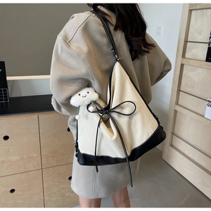Side view of large canvas tote bag with black leather straps and a plush cloud charm