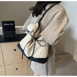 Canvas tote bag with black leather trim and bow detail shown on a female model