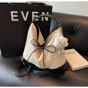 Detailed shot of cream canvas tote bag with black leather base and plush cloud charm