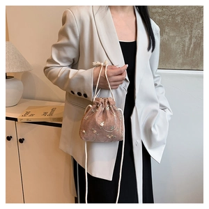 Dettaglio del ricamo floreale su una borsa a secchiello con coulisse in tessuto rosa