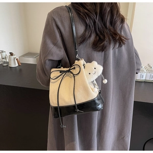 Detail of canvas bucket bag with black leather base and cute white plush bear charm
