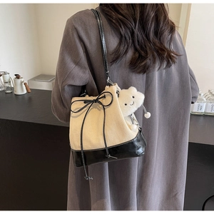 Detail view of beige herringbone canvas bucket bag with black leather trim and bow