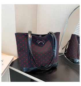 Detail of black tote bag with red heart embroidery and silver metal bow ornament
