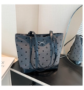 Detail of grey polka dot tote bag with silver metal bow and black leather straps