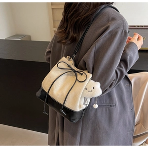 Detail of a drawstring bucket bag with beige canvas, black leather and cloud charm