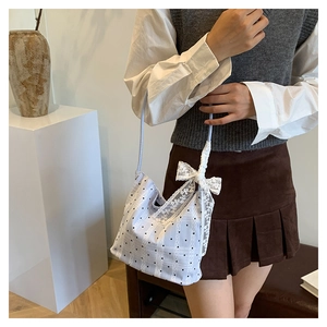 Close-up of white bucket bag featuring black polka dots and oversized lace bow detail