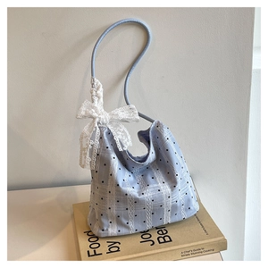 Detail of light blue polka dot bucket bag with a large white lace bow and shoulder strap
