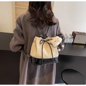 Detail of a beige and black bucket bag with drawstring closure and cloud charm