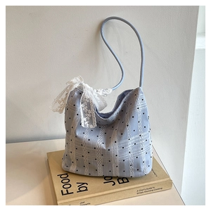 Detail of light blue bucket bag with black polka dots, lace trim and a large white bow