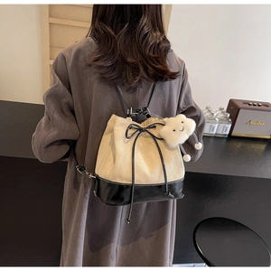 Detail of canvas bucket bag with black leather base, drawstring bow and cloud charm