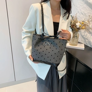 Chic grey tote bag with black polka dots and silver bow charm shown on model