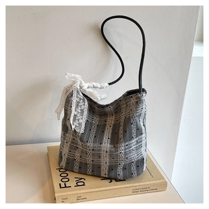 Detailed view of grey checkered bucket bag with white lace ribbon and polka dot mesh textures