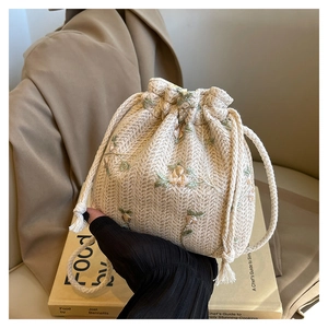 Dettaglio della borsa a secchiello in paglia intrecciata con ricamo floreale e coulisse