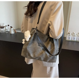 Détail du sac cabas en toile grise rétro avec logo en cuir et pendentif nuage peluche