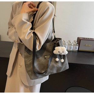 Détail d'un grand sac cabas gris foncé avec texture vintage et breloque peluche nuage blanc