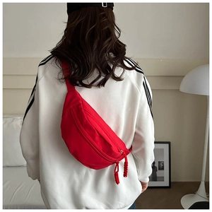 Close-up of bright red canvas crossbody chest bag with woven drawcord double zippers