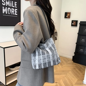 Minimalist woven bucket bag with black polka dots and slim leather shoulder straps