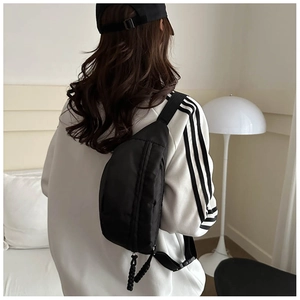 Detail of black nylon chest bag with woven rope zipper pull on wide shoulder strap
