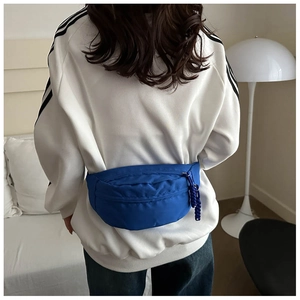 Blue nylon crossbody waist bag shown on model with adjustable strap and zip detail