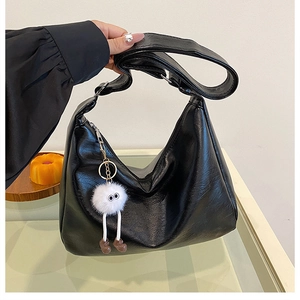 Detailed side view of black PU leather hobo bag with a cute white plush monster charm