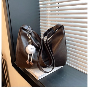 Detail der weichen dunkelbraunen PU-Leder Shopper Tasche mit weißem Plüsch-Anhänger Dekor