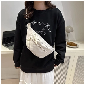 Detail of off-white canvas crossbody bag with dual zippers and woven cord pullers