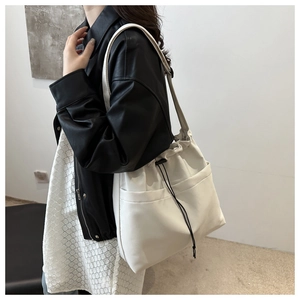 Fashionable beige large capacity tote bag with drawstring closure shown on shoulder