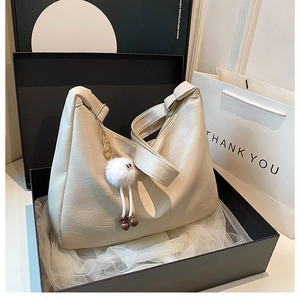 Detail der beige hobo tasche mit litschi-narbe und plüsch-anhänger in geschenkbox
