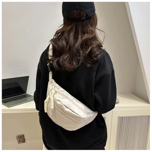 Close-up of beige nylon crescent crossbody bag with woven pullers on a model's back