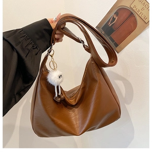 Detail der braunen Hobo-Tasche aus Kunstleder mit Lychee-Muster und Plüsch-Anhänger