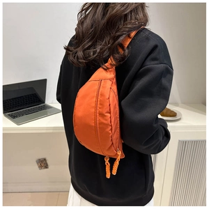 Detail of vibrant orange nylon crossbody chest bag with hand-woven zipper pullers