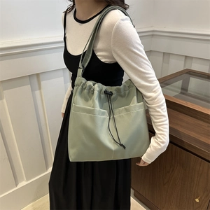 Light green nylon tote bag with drawstring closure and large front pockets for daily commute