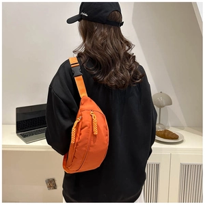 Detail view of the bright orange nylon crossbody chest bag with adjustable strap and buckle