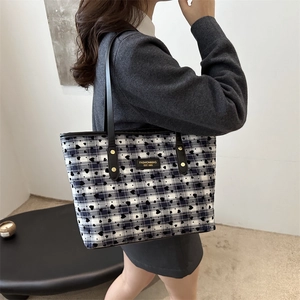 Large plaid tote bag with heart patterns and black straps shown on model for daily use