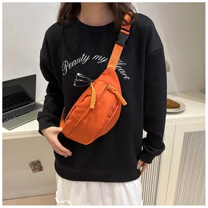 Detail of bright orange nylon crossbody chest bag with adjustable strap and buckle