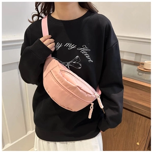 Detail view of pink nylon crescent waist bag with zipper and woven strap on model
