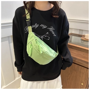 Lime green nylon crossbody chest bag with adjustable strap worn by model in casual setting