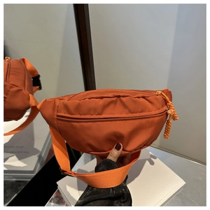 Detailed close-up of orange nylon waist bag texture and adjustable strap buckle
