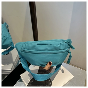 Detail of teal blue nylon waist bag showing woven zipper pulls and matte fabric texture