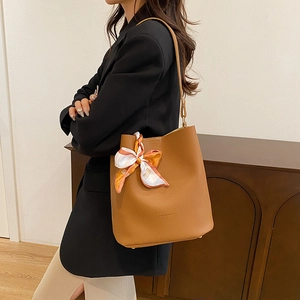 Classic brown textured leather bucket bag with printed silk scarf on model's shoulder
