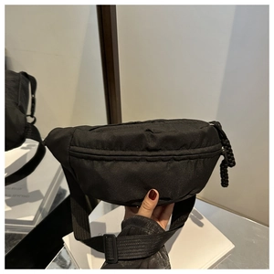 Detail of black waterproof nylon waist bag with woven zipper pull and adjustable strap