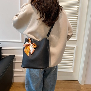 Chic black bucket bag with lychee texture and silk scarf handle, shown on model