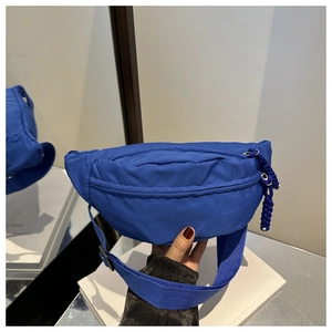 Detailed close-up of blue nylon waist bag featuring dual zippers and adjustable wide strap