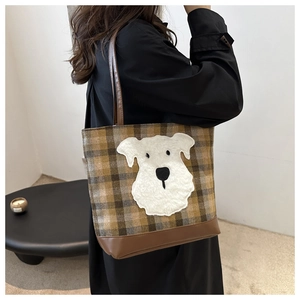 Detail of vintage plaid tote bag with cute dog plush patch on model shoulder
